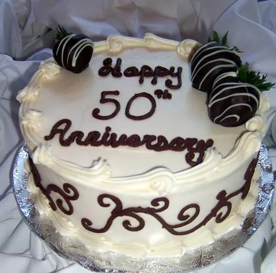 White 50th anniversary cake with chocolate-dipped strawberries