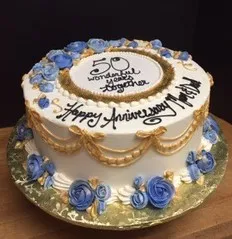 Anniversary cake decorated with blue roses and gold piping
